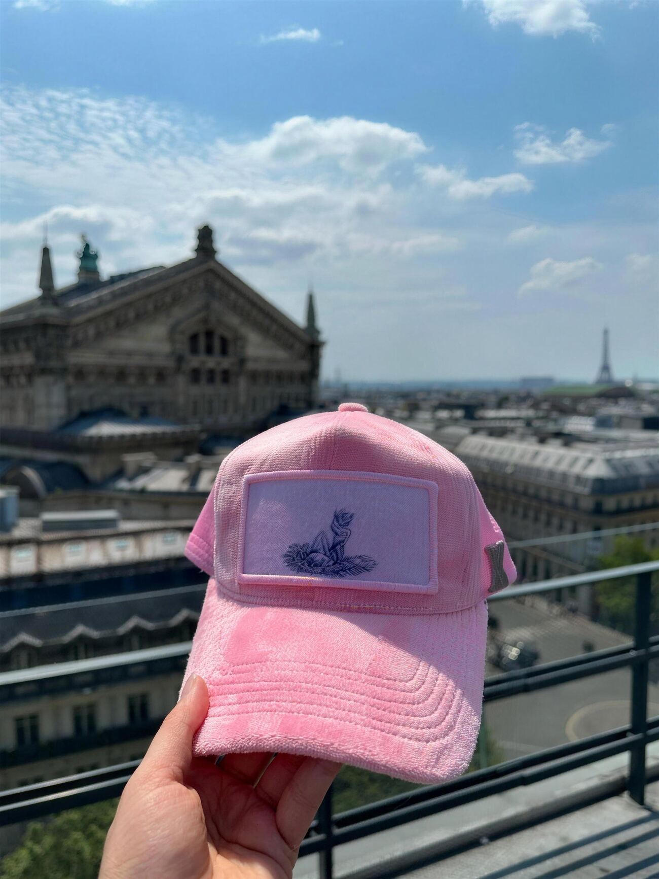 Powder pink velvet trucker cap with an ink-sketched fox patch, with the Palais Garnier and the Eiffel Tower behind it