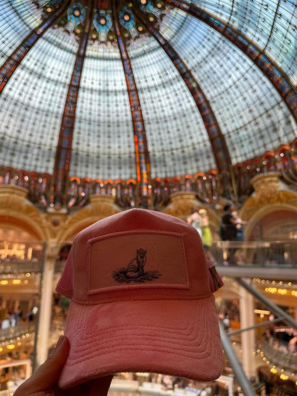 Pink velvet trucker cap with a fox sketch patch under the stained-glass dome of the Galeries Lafayette